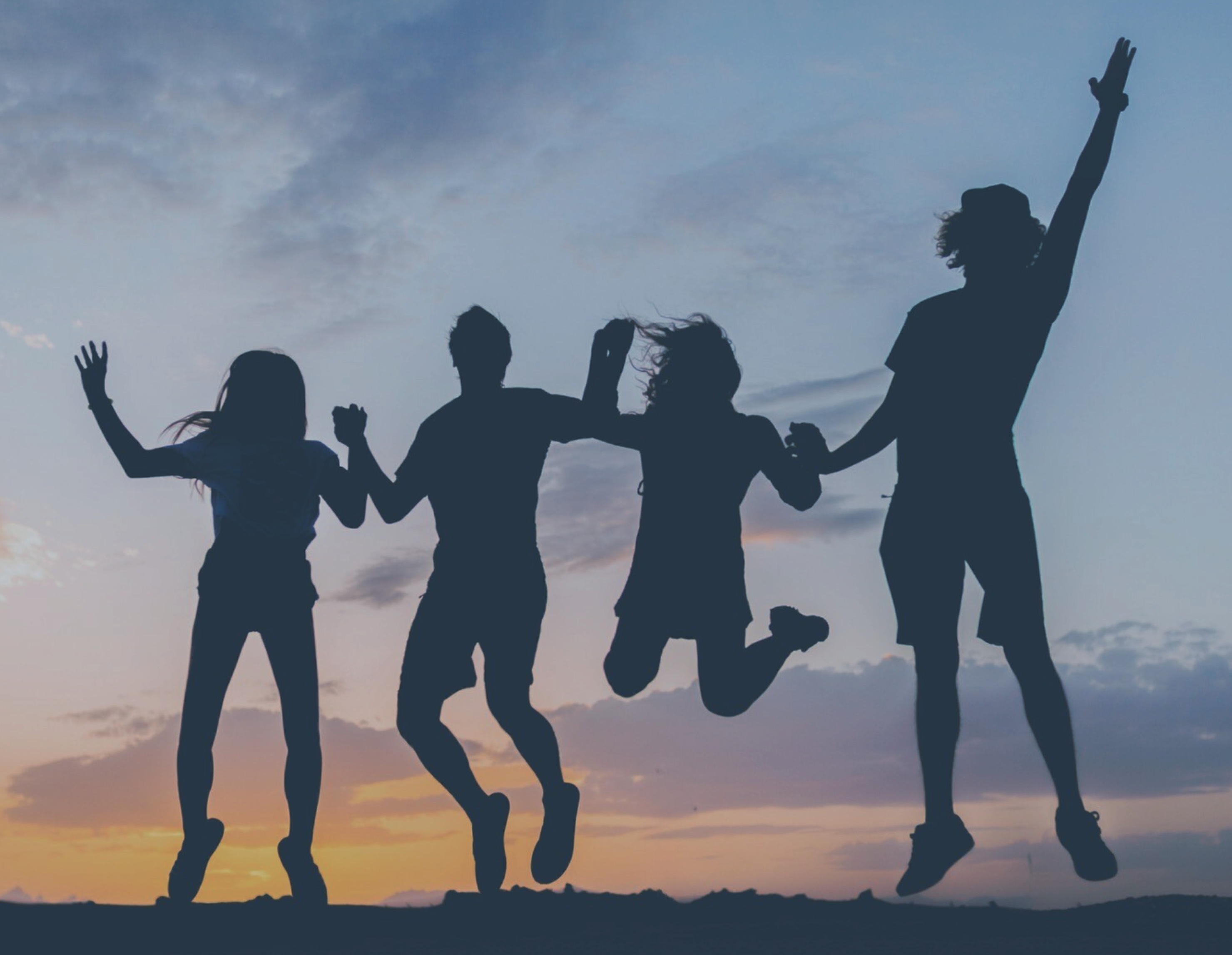 Fyra människor tar ett hopp i motljus