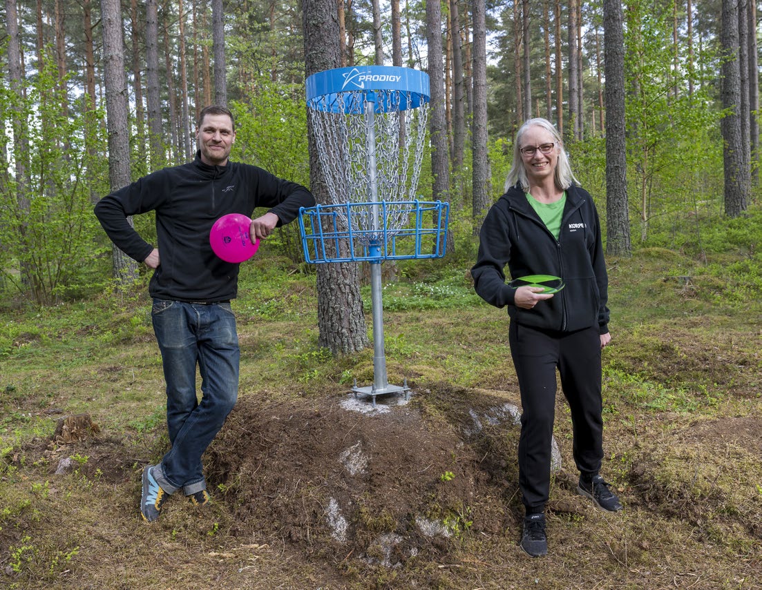 Fredrik och Malin vid ett discgolfbanehål i skogen