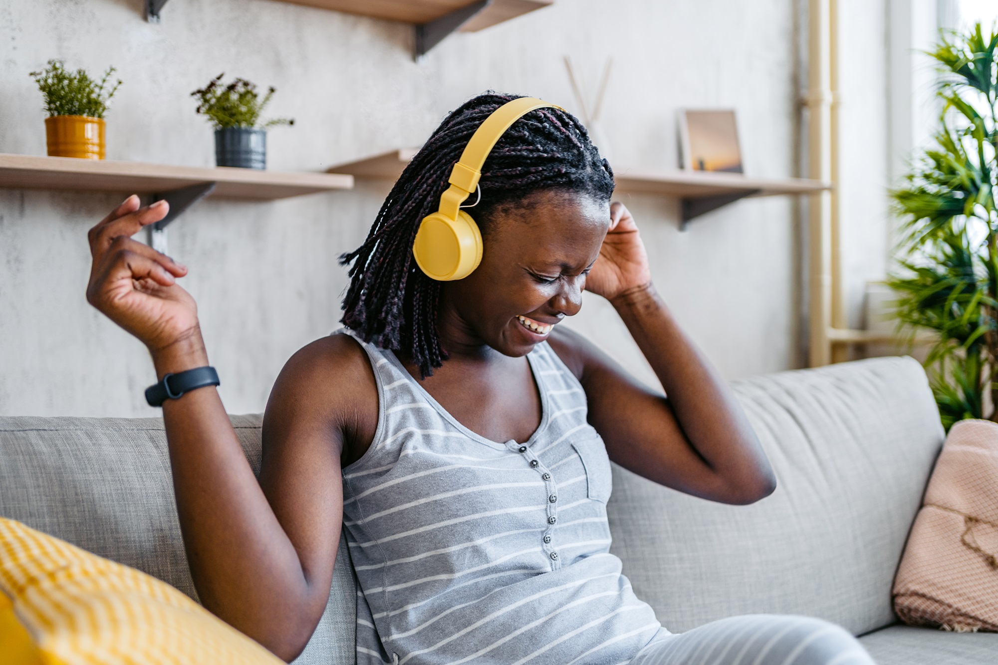 Kvinna sitter i en soffa och lyssnar på musik i sina hörlurar