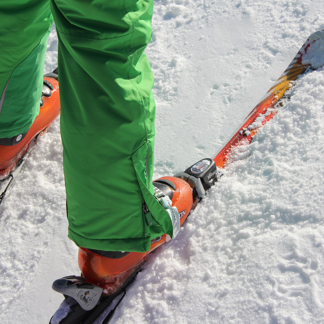 Nederdelen på person med pjäxor och skidor i snö